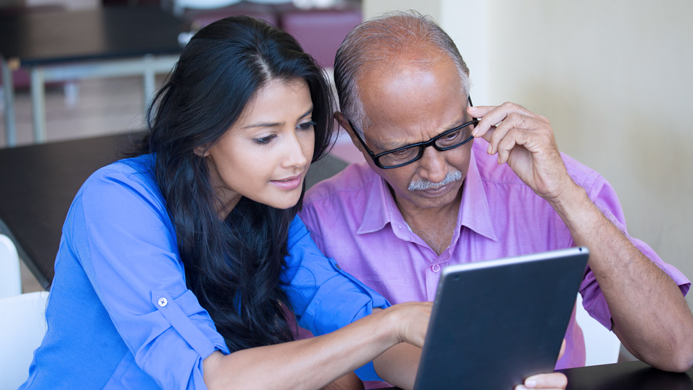 A woman and her father sit at a table and look over probate documents.