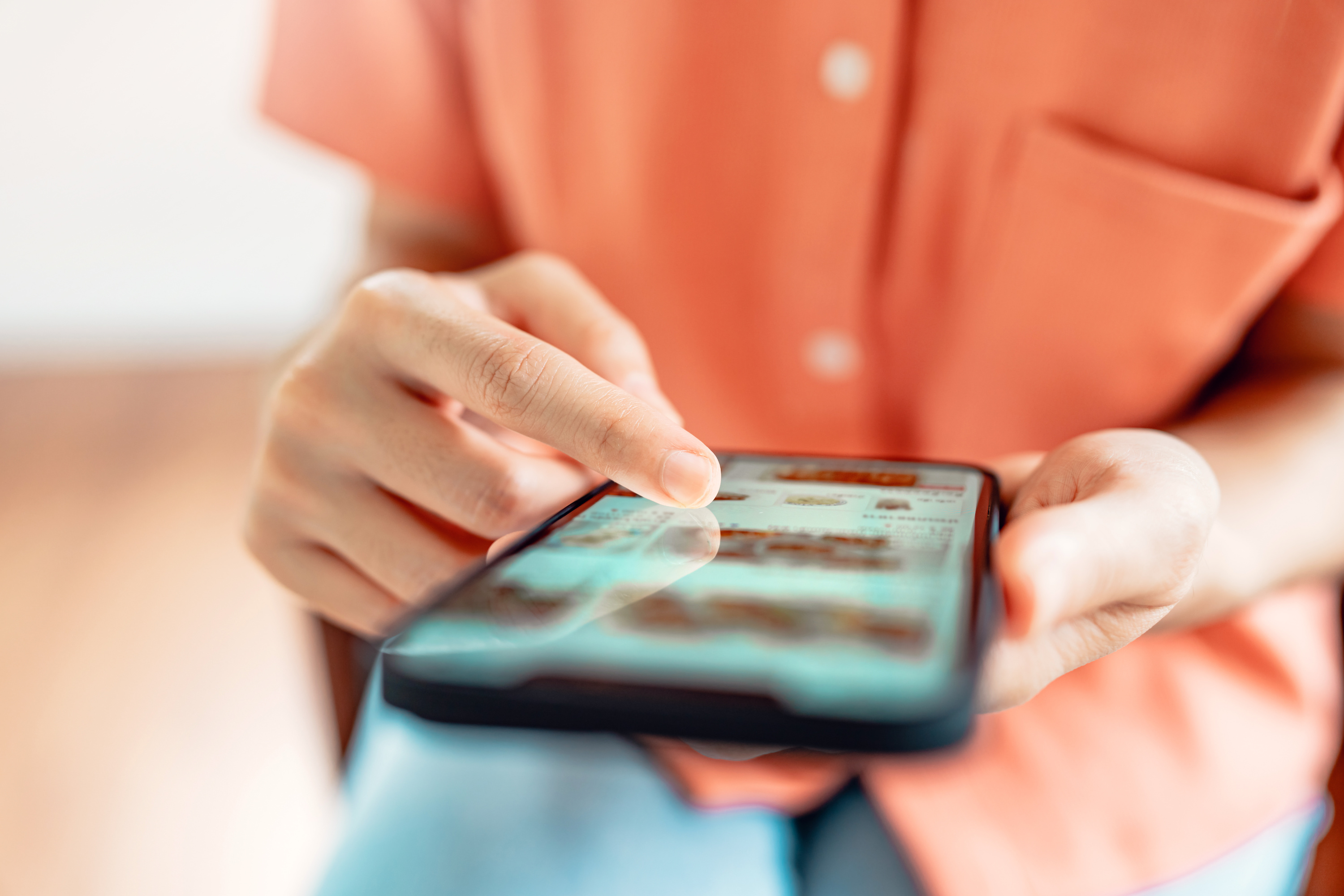 Social media marketing activities, such as posting content, engaging with followers, and running targeted ads, can aid small businesses. A woman holding a smartphone interacts online with her customers.
